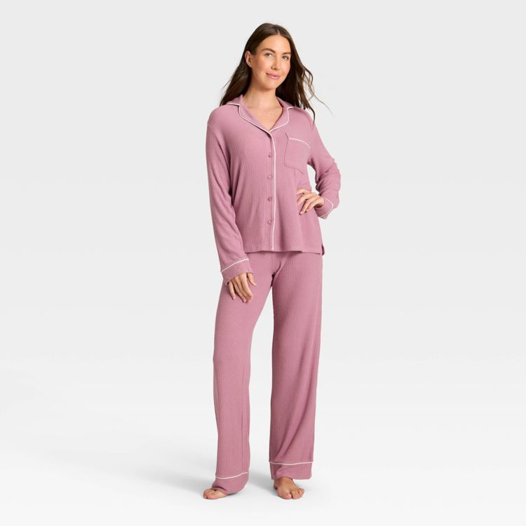 Pink colored pajama set with a button-up top and long pants, featuring white trim details.