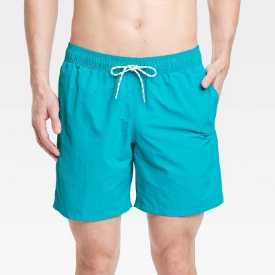 Tanned and fit senior man wearing blue swim trunks and a pair of