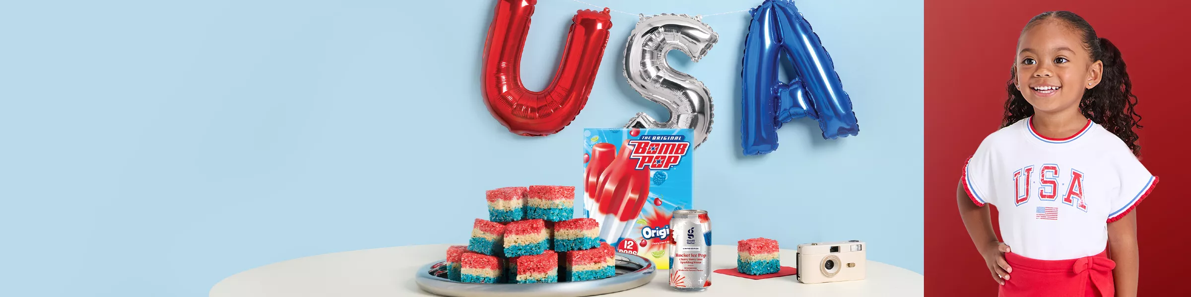 USA balloon in red, silver and blue. Over a table with red, white and blue rice treats. Along with bomb pops popsicles and a rocket pop good & gather flavored water.