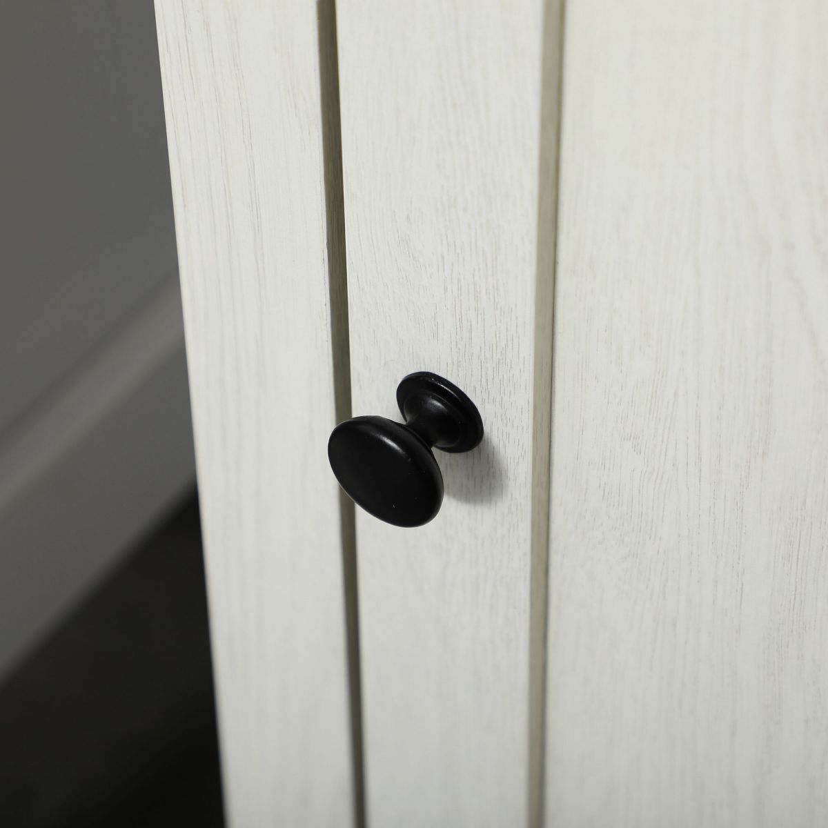 Close-up of black cabinet knob on white cabinet