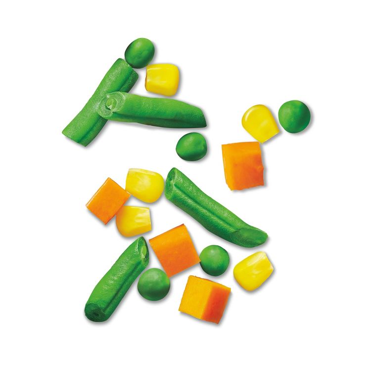 Green beans, peas, corn, and carrot pieces scattered on a white background.