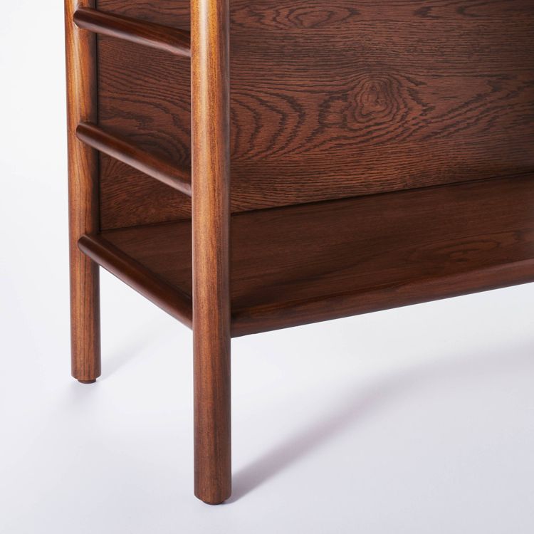 A close-up of a dark brown colored wooden bookcase corner with visible wood grain and rounded legs.