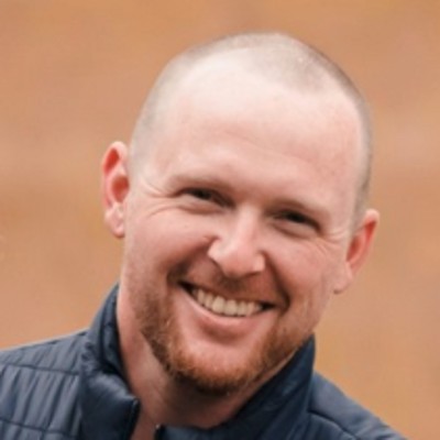 Headshot of Jeffrey Bursik, a man with pale skin and shaved head. Photographed against a neutral backdrop.