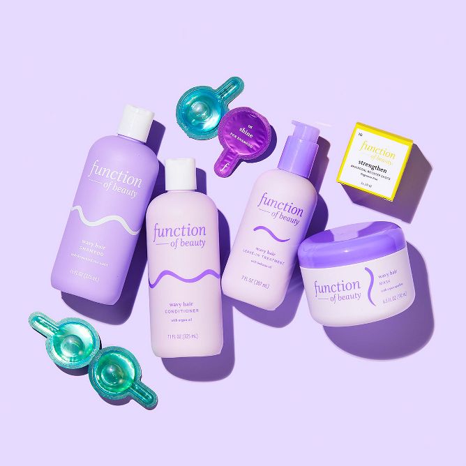 A collection of personalized hair care products by Function of Beauty on a purple background, including shampoo, conditioner, a leave-in treatment, a hair mask, and a serum.